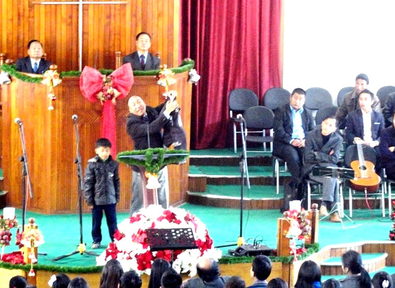 CBCMHK, Pastor, Dr. Vevo Phesao displays the jacket to the congregation. Mulutso is seen standing in the left. (Morung Photo)